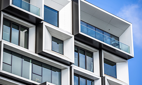 Street scene of the modern city with wall of a multistory apartment building with decorative trimming in the form of squares in geometric grid and protruding modular facade