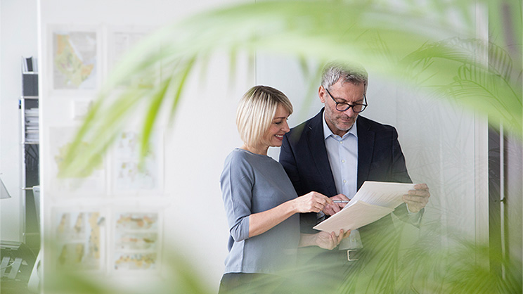 Businessman and woman working together in office discussing documents