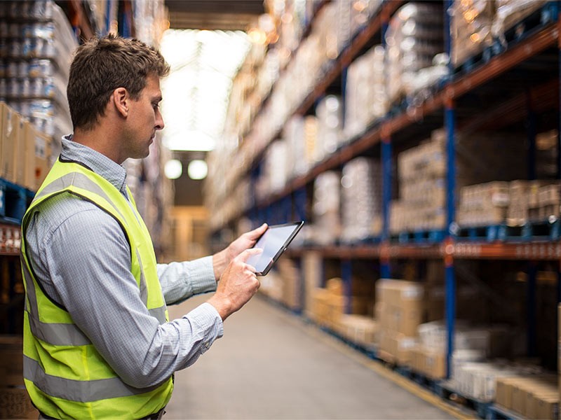 Warehouse worker on tablet analysing stock