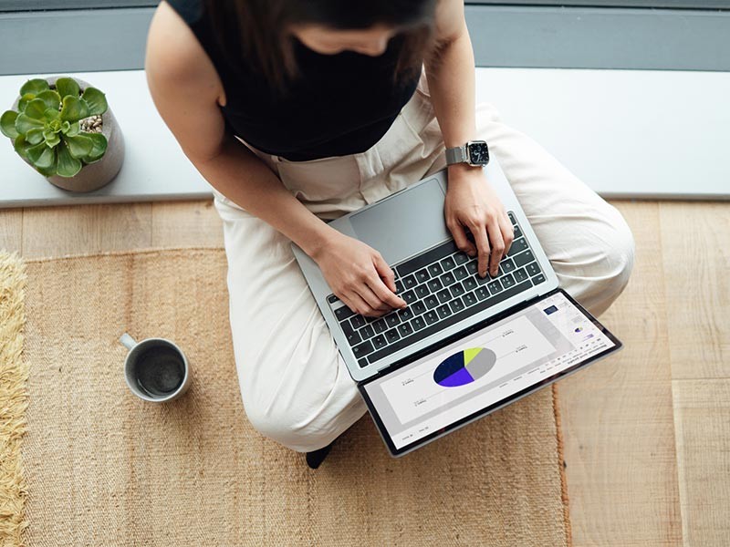 Woman typing on laptop, sitting on the floor