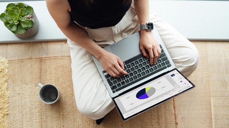 Woman typing on laptop, sitting on the floor