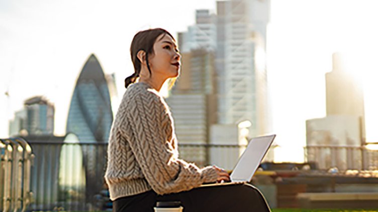 Young woman with laptop working on roof terrace