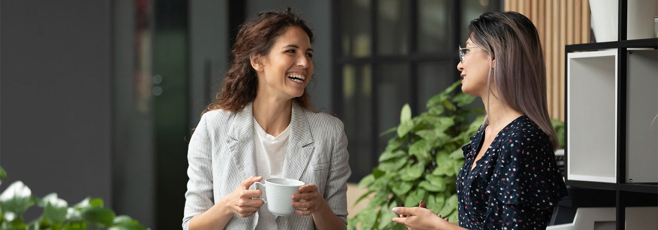 Two female employees talking while having coffee inside the JLL office premises